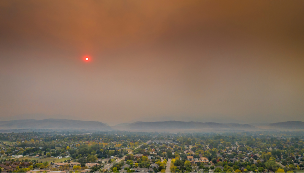 Red sun over town and mountains with smoky skies from forest fire